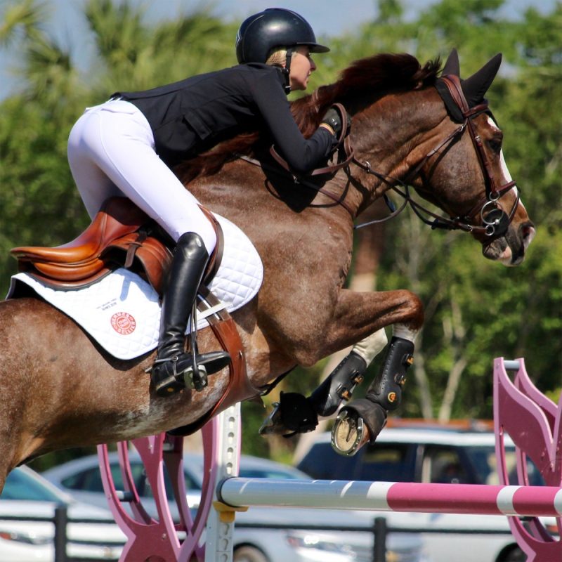 Equestrian rider jumping a horse in tall boots